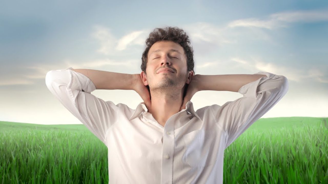 Joven en medio de un campo con rostro de tranquilidad